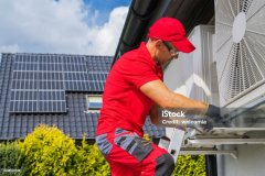 HVAC Worker Performing Heat Pump Maintenance. Device is Transferring Thermal Energy From the Outside Using the Refrigeration Cycle. Home Heating Technologies.